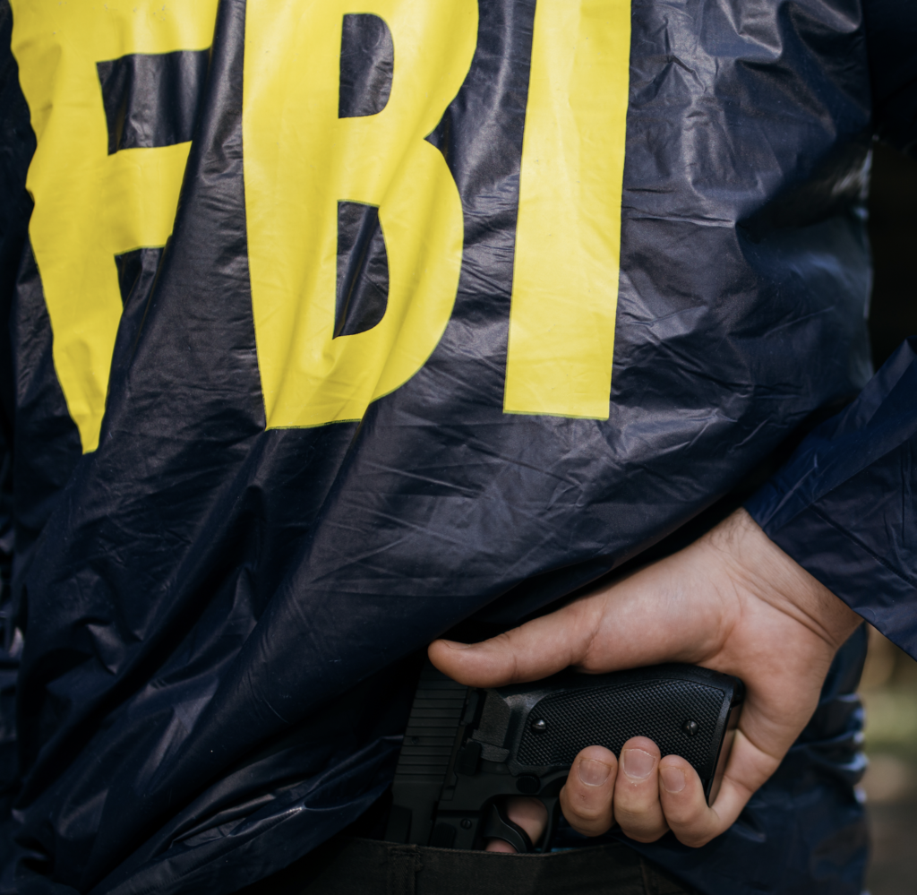 An FBI agent holding a gun from behind