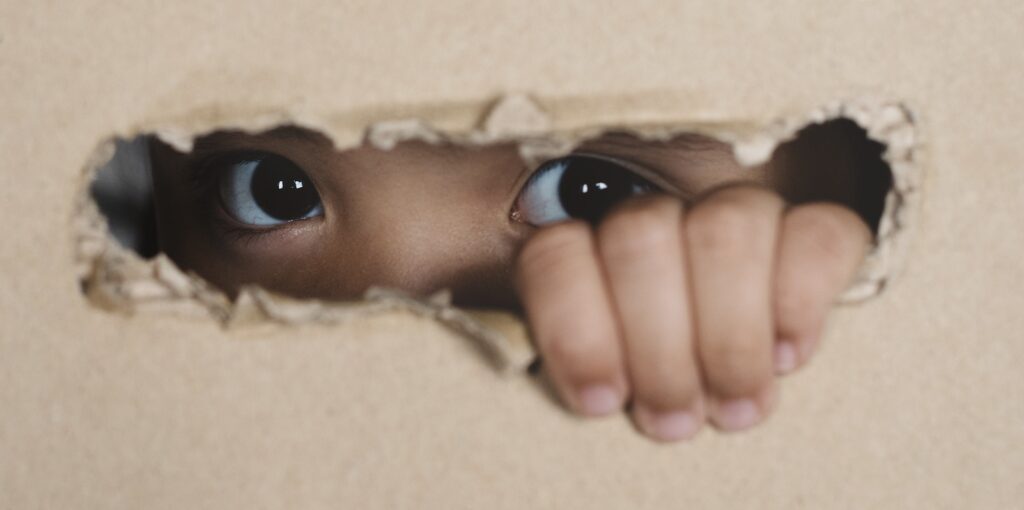 A child peaking from the hole in the wall