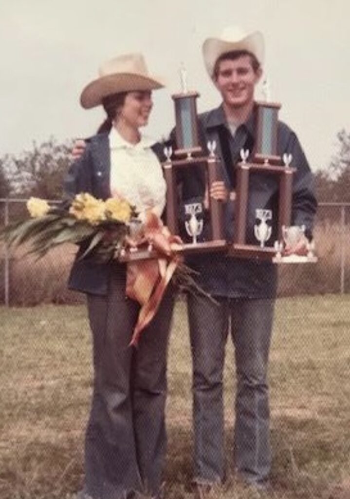 Two people in cowboy hats holding trophies.