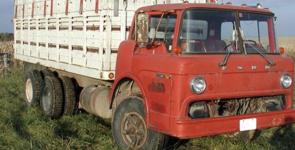 An old red truck is parked in a field.