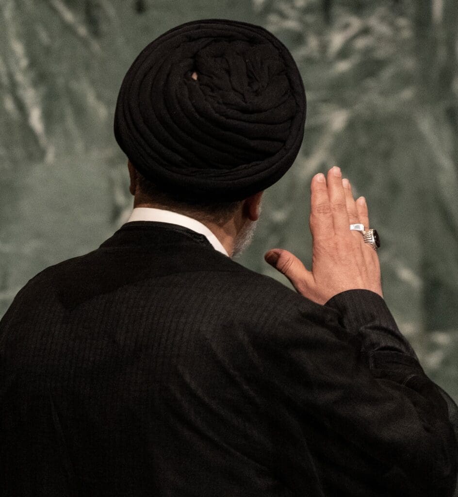 Man in black turban raising his hand.