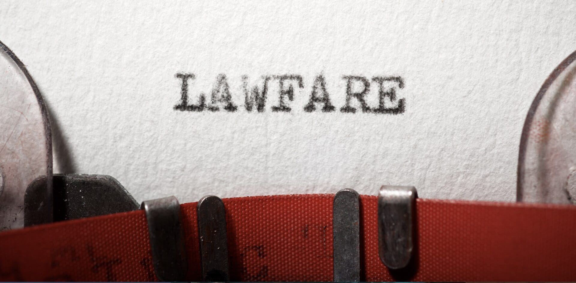 The image shows a close-up of a typewriter printing the word "lawfare".