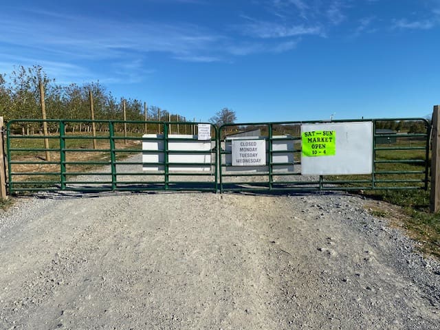 Green gate with market hours signage.