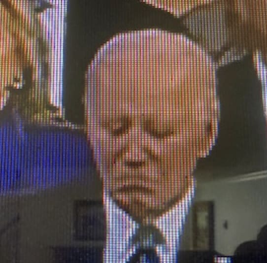 Man with a solemn expression on TV.