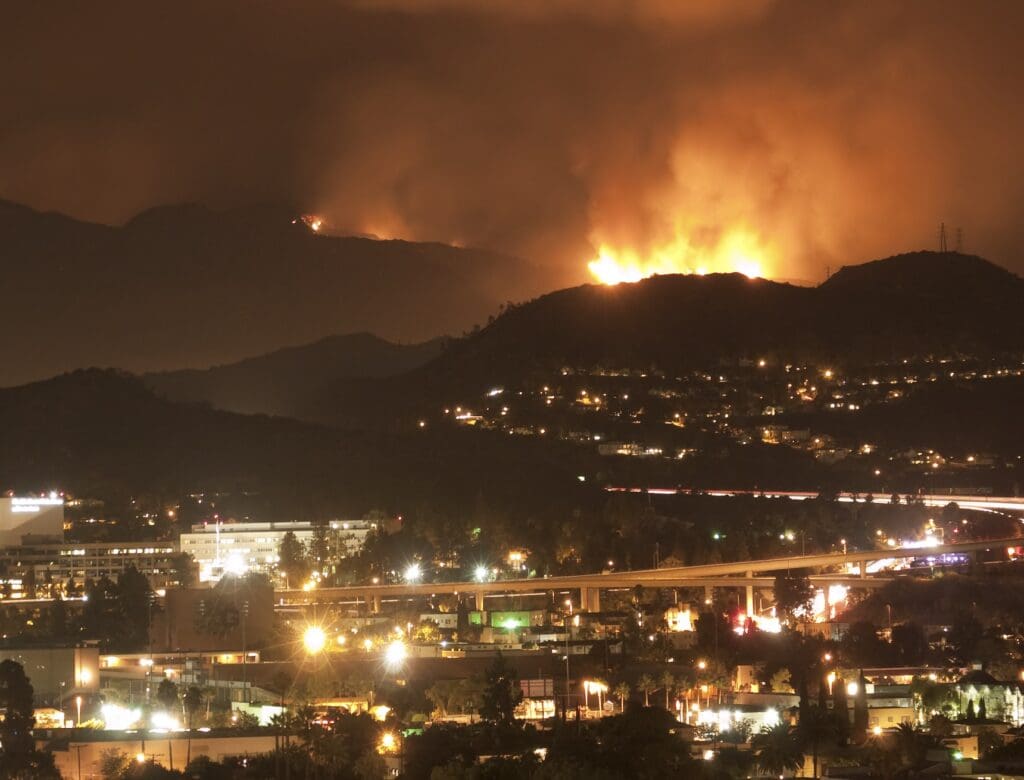 Wildfire burning on distant mountains at night.