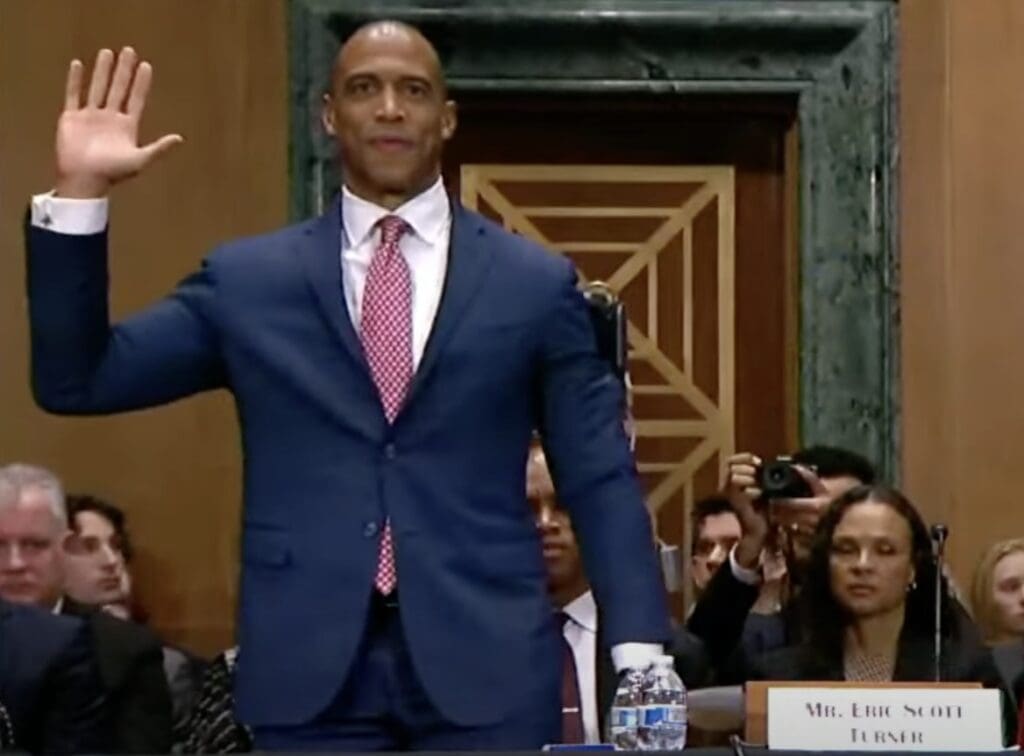 Man in suit raising hand in testimony.