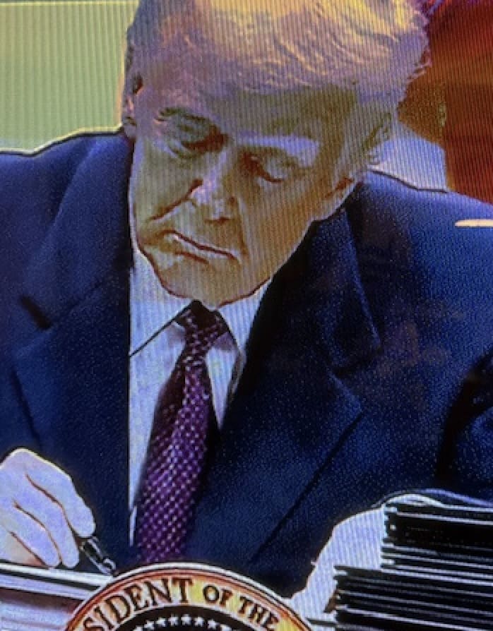 Person signing documents at a desk.