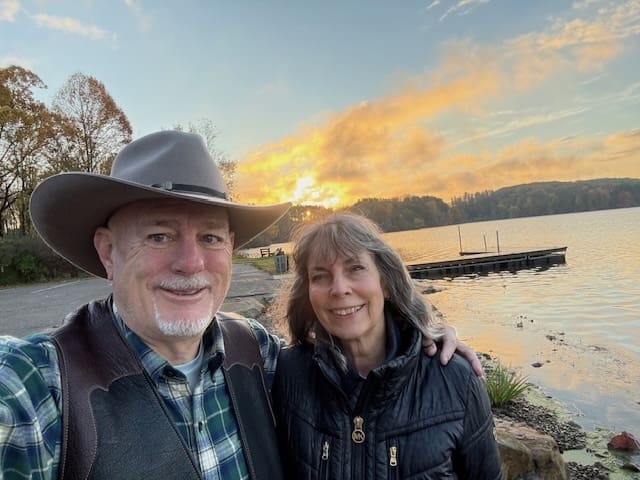 Couple smiling by a lake at sunset.